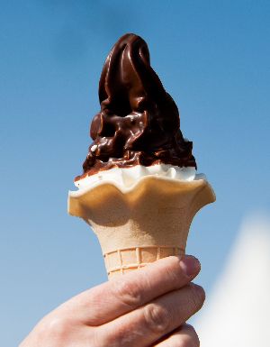 Vanille Softeis im Waffelbecher mit einem Schokomantel überzogen.